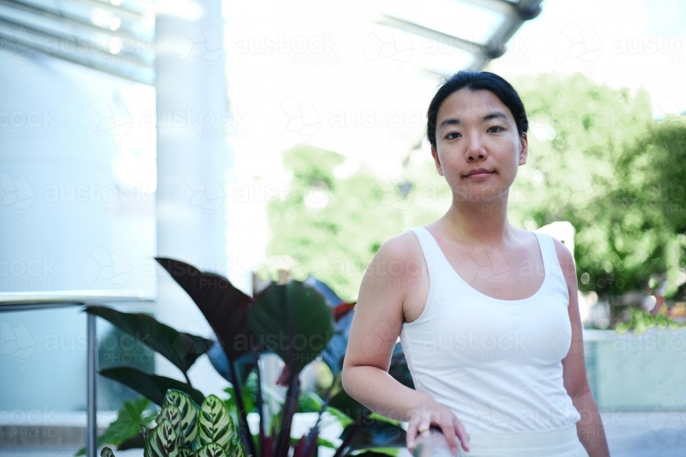 Asian woman standing along the walkway outdoors - Australian Stock Image