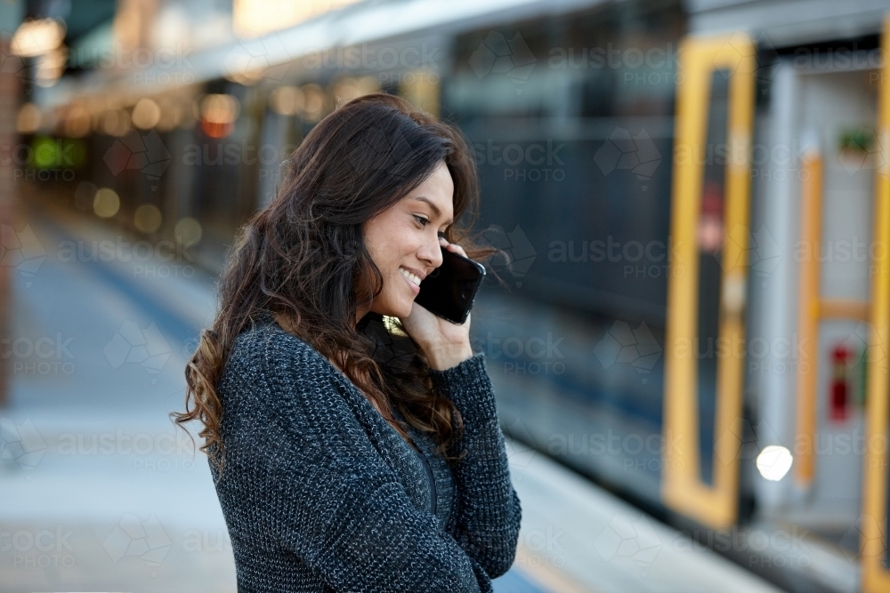 Asian woman talking on phone at train station - Australian Stock Image