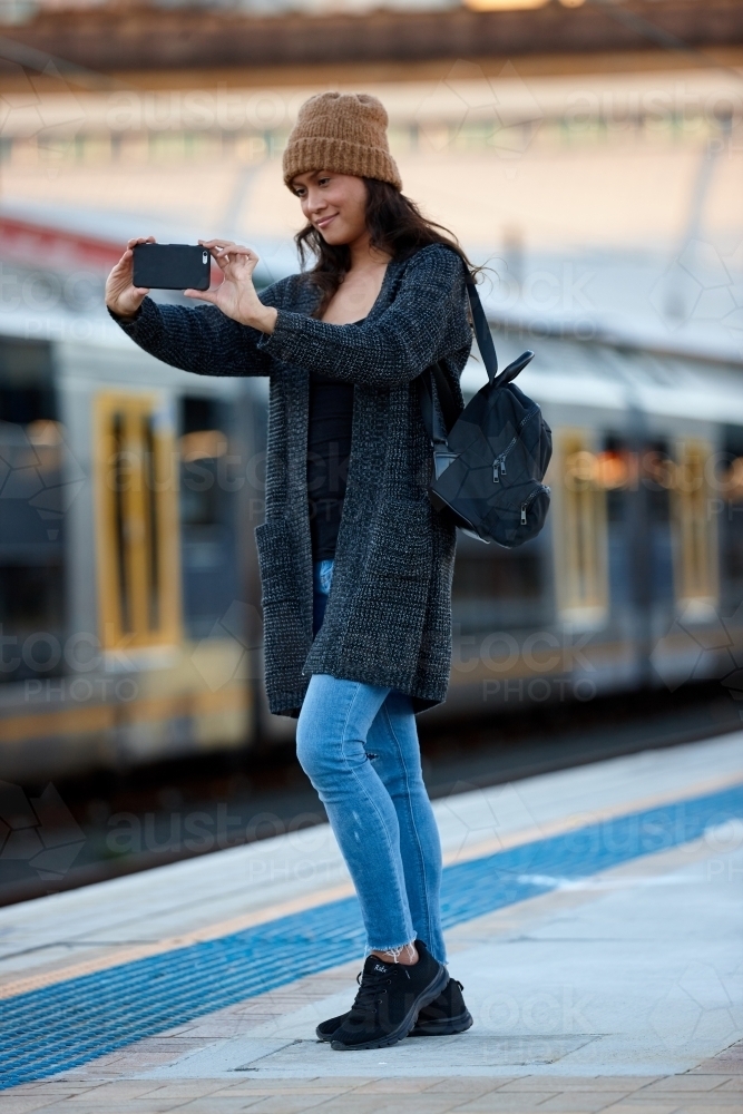 Asian woman talking photo with phone at train station - Australian Stock Image