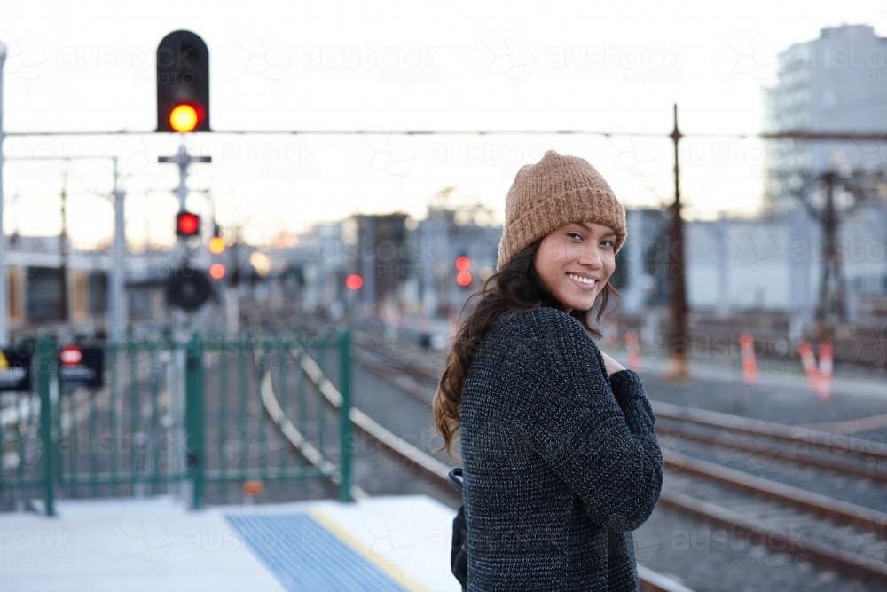 Asian woman waiting at train station during winter - Australian Stock Image