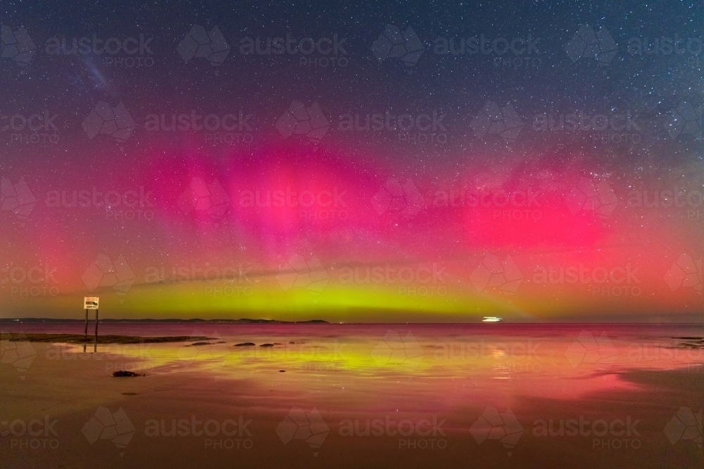 Aurora Australia illuminating the night sky and reflecting on a wet sandy beach - Australian Stock Image