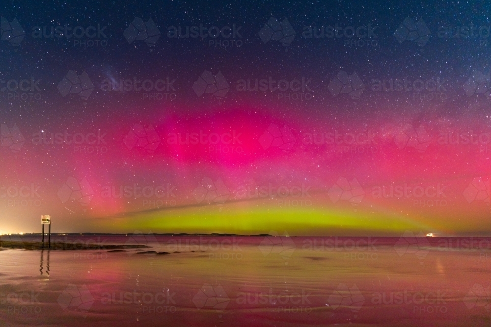 Aurora Australia illuminating the night sky and reflecting on a wet sandy beach - Australian Stock Image