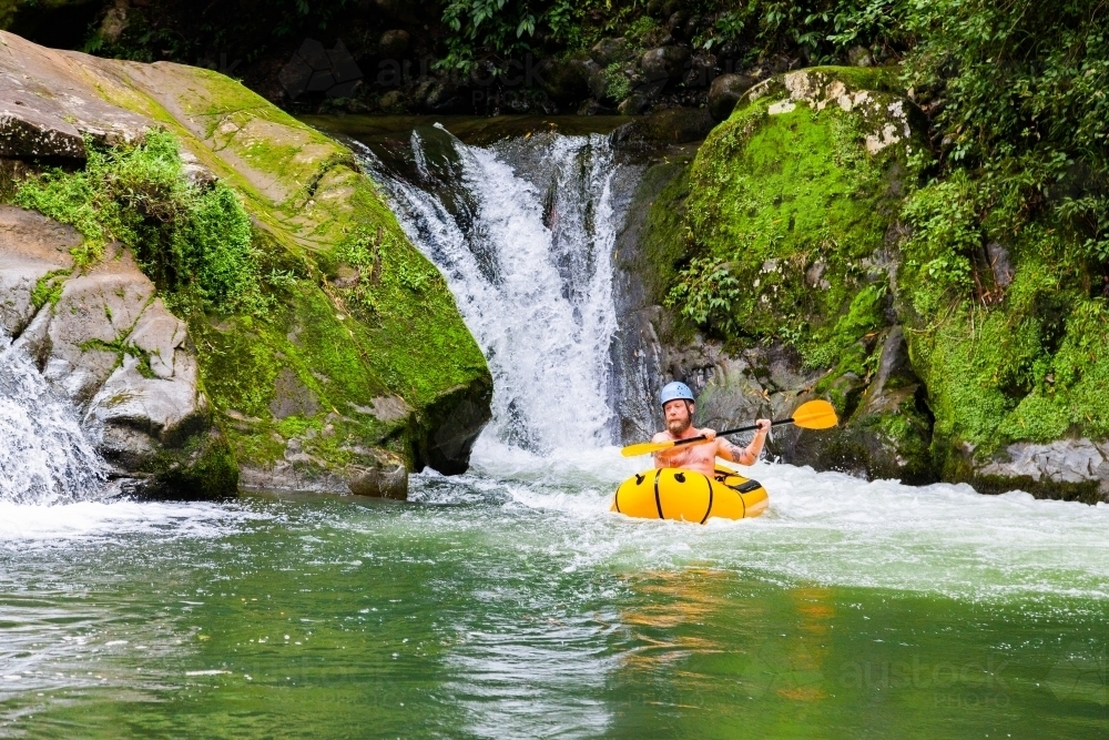 Aussie adventurer paddling down mountain stream in inflatable kayak - Australian Stock Image