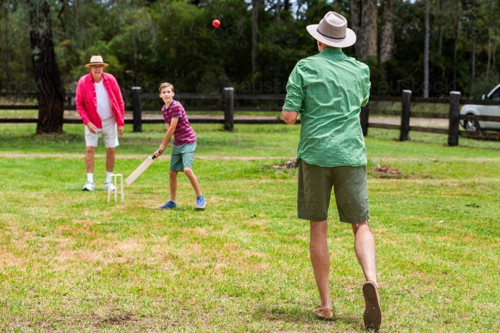 Image of Aussie boy playing backyard cricket with dad and grandfather ...