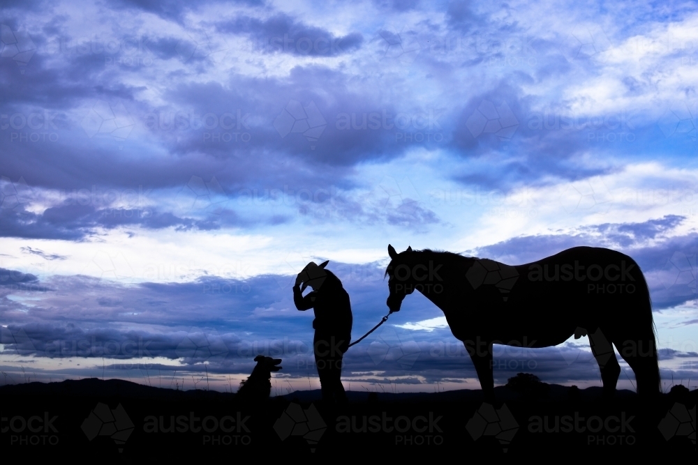 Aussie country scene at sunset with young woman horse and dog on ridgeline - Australian Stock Image