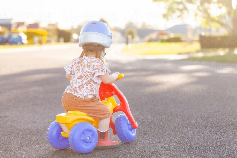 Aussie kid riding tricycle outside on quiet suburban road - Australian Stock Image