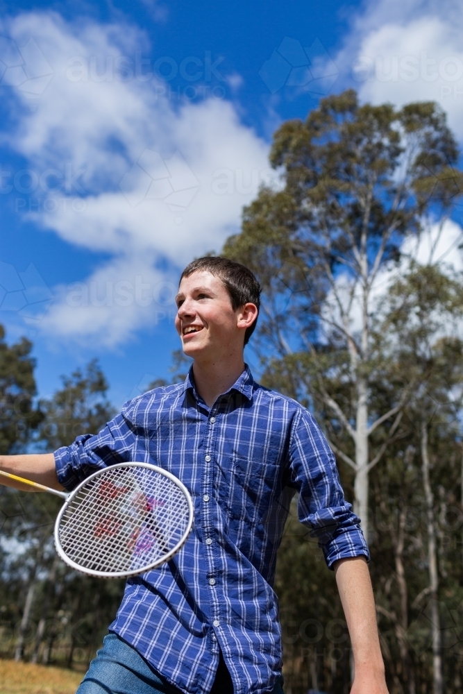 Aussie teen with racquet playing badminton in rural backyard in spring sunshine - Australian Stock Image