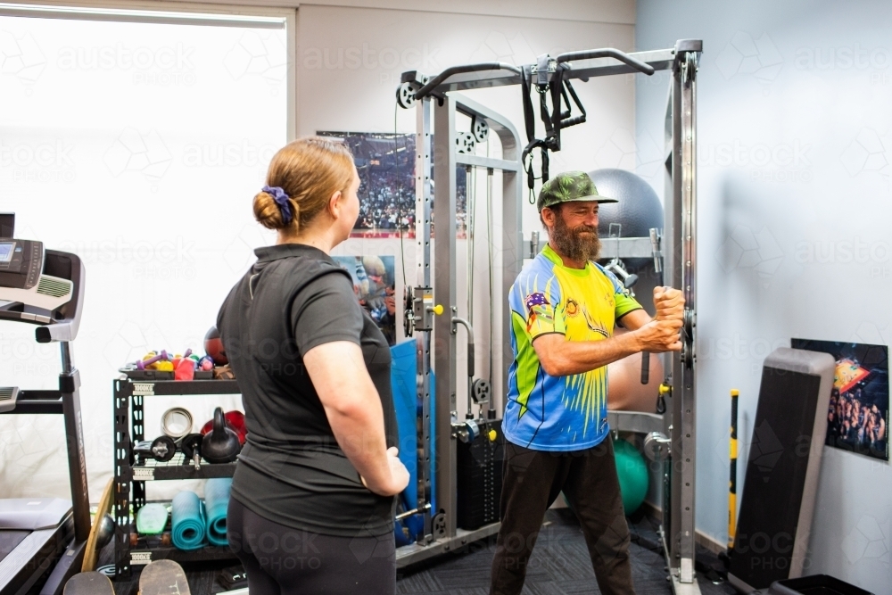 Australian aboriginal man doing physiotherapy with physio practitioner guiding exercises - Australian Stock Image