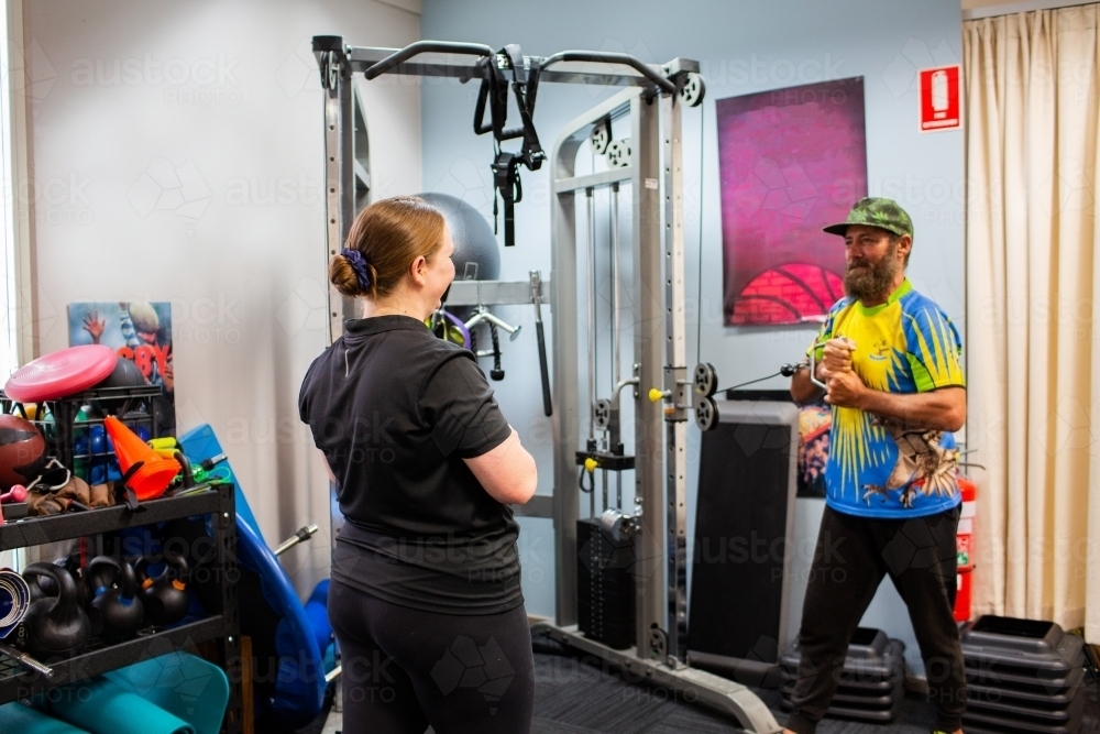 Australian aboriginal man doing physiotherapy with physio practitioner guiding exercises - Australian Stock Image