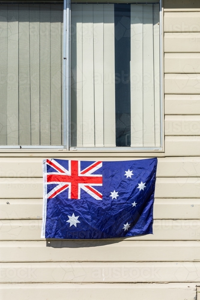 Australian flag on wall of sunlit weatherboard house - Australian Stock Image