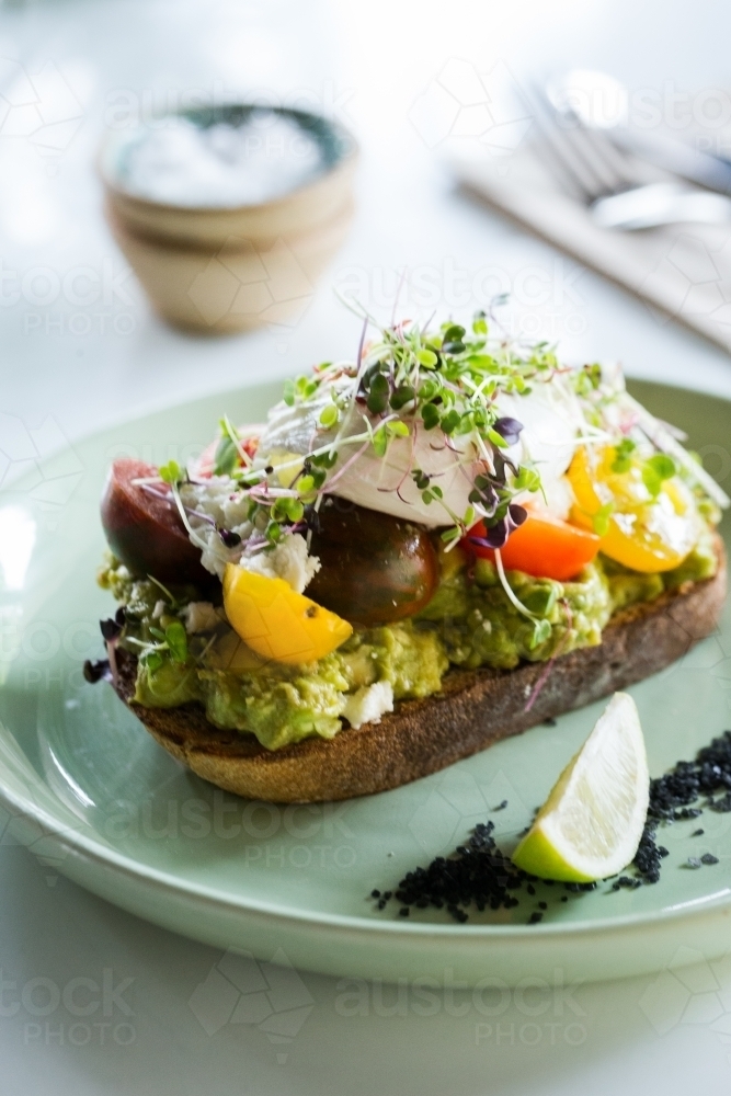 Avocado toast on a plate with tomatoes and lime - Australian Stock Image