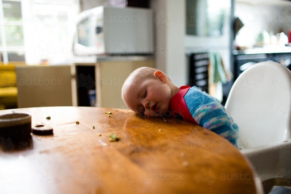 Baby asleep at the kitchen table - Australian Stock Image