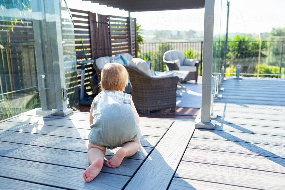 Baby crawling towards unsafe open pool gate in aussie backyard - Australian Stock Image