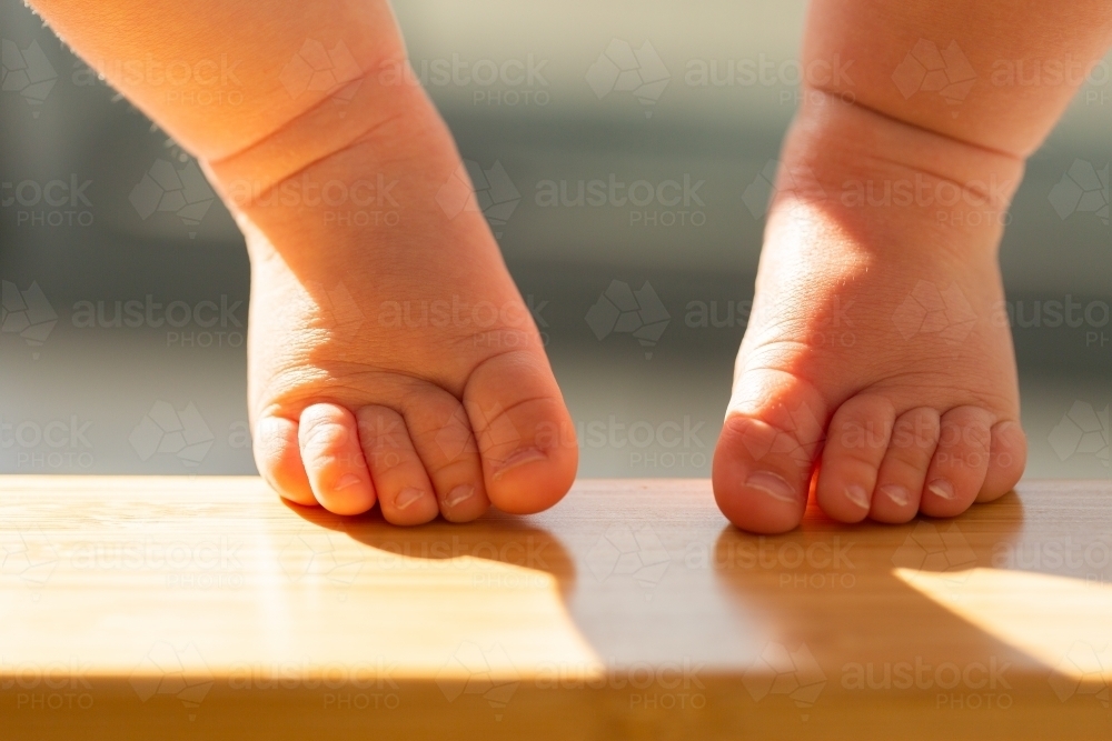 Baby feet and toes resting on high chair foot rest - Australian Stock Image