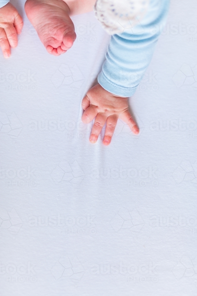 Baby hand and foot with copy space on white sheet - Australian Stock Image