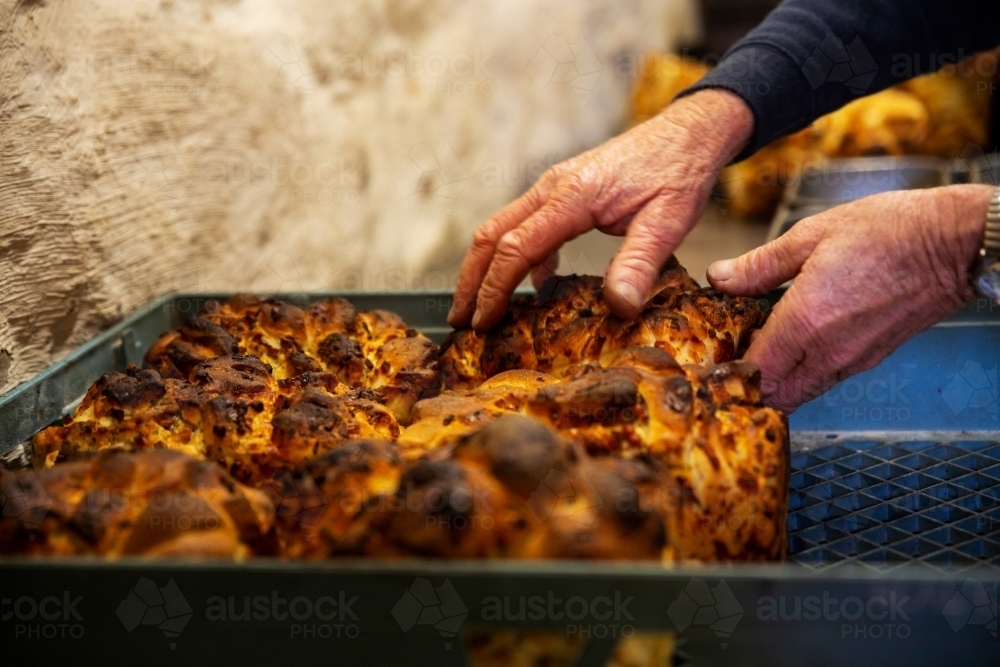 baker's hands touching bread loaf - Australian Stock Image