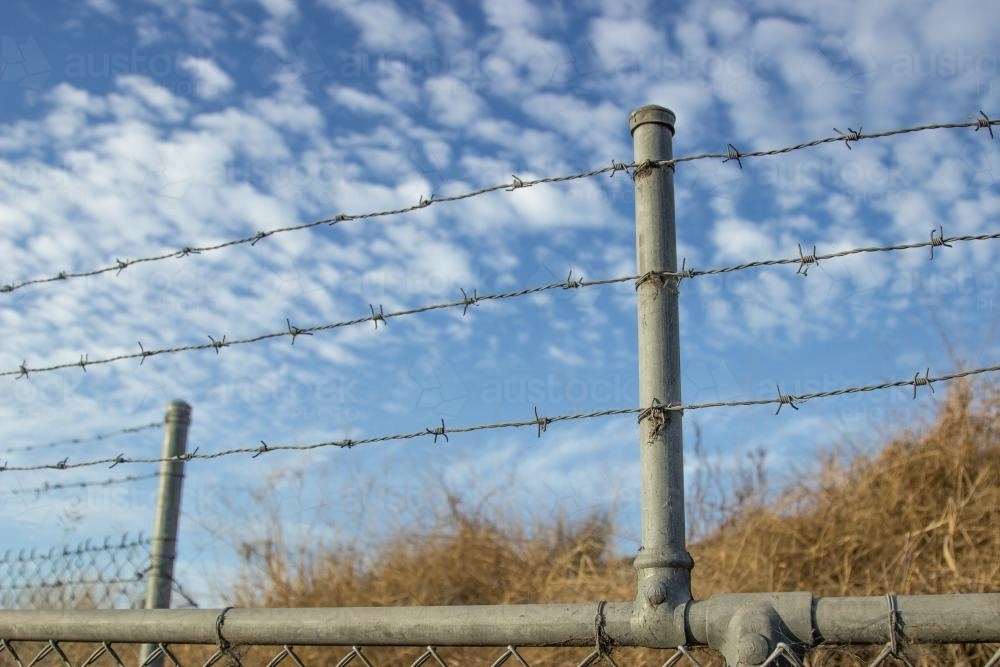 Barbed wire fence with clouded sky - Australian Stock Image