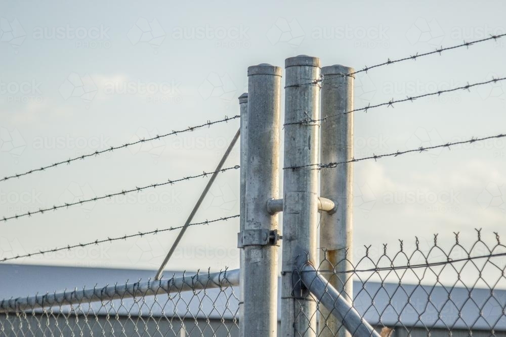 Barbed wire industrial fence and gate - Australian Stock Image