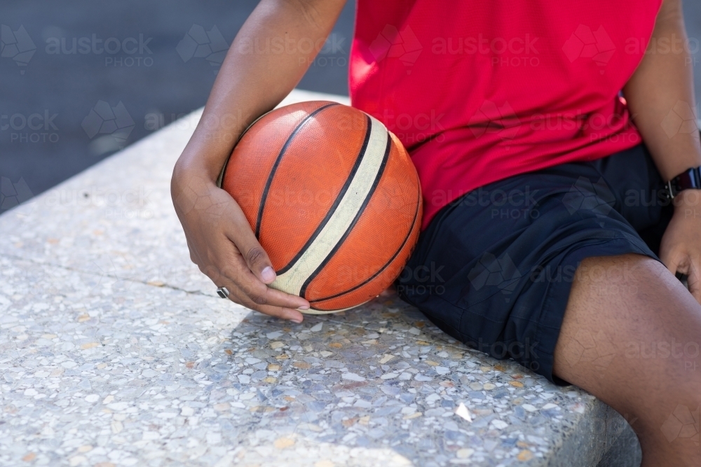 basketball being held by player on sidelines - Australian Stock Image