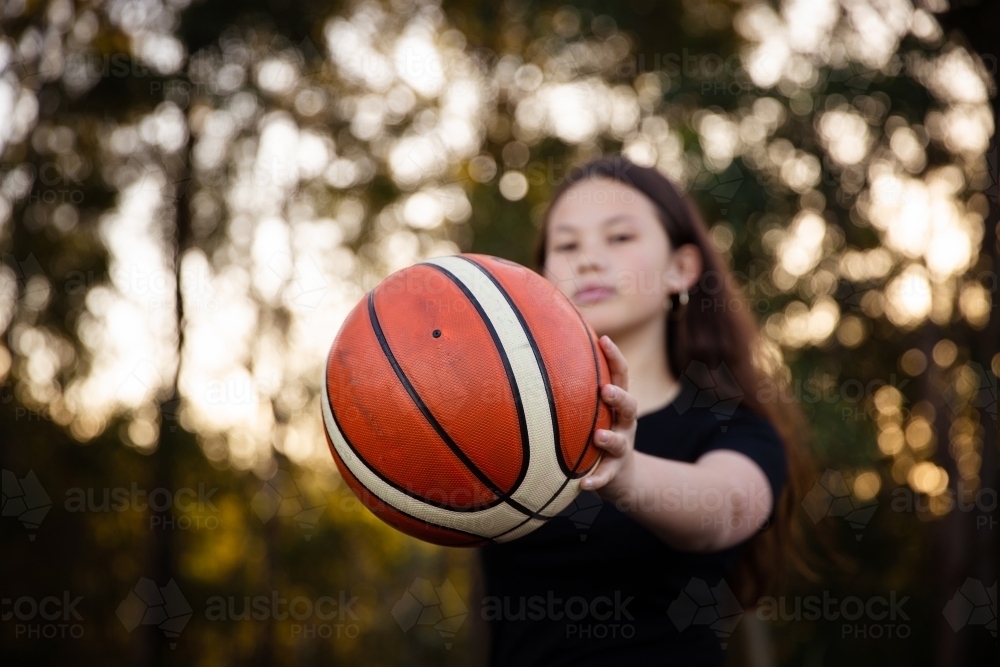 basketball close up held out by teen girl - Australian Stock Image