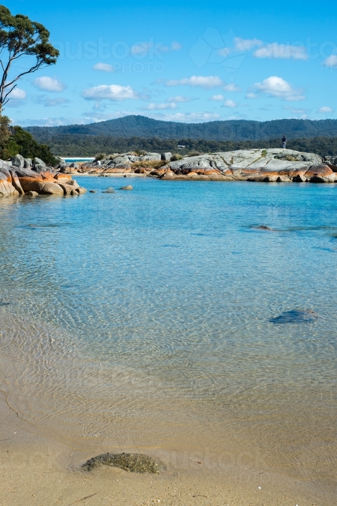 Bay surrounded by rocks and trees with clear water on sunny day - Australian Stock Image