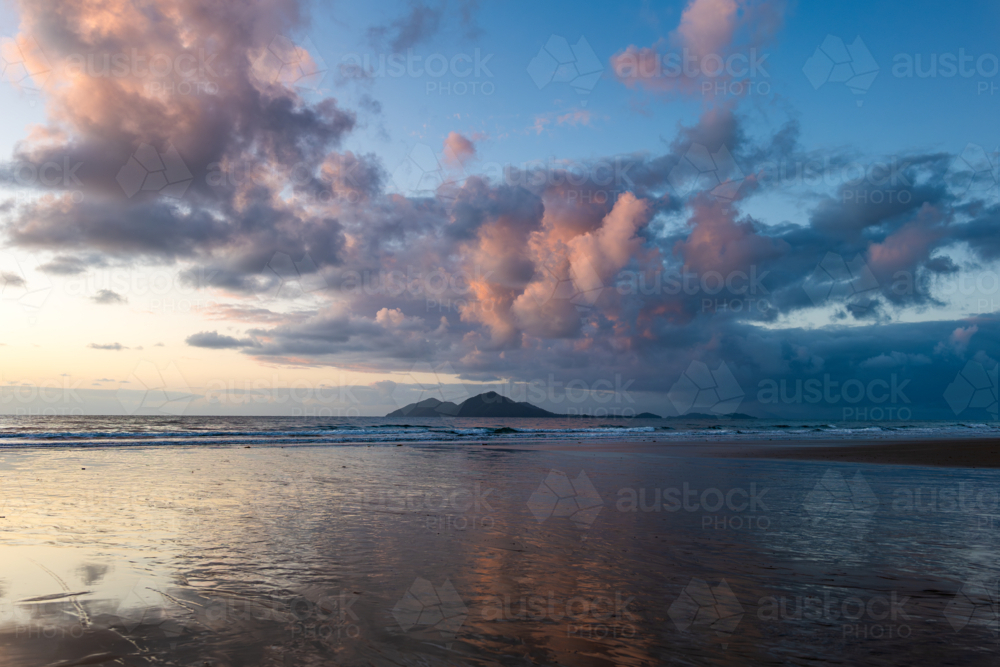 Beach scene at sunrise with waves and island - Australian Stock Image