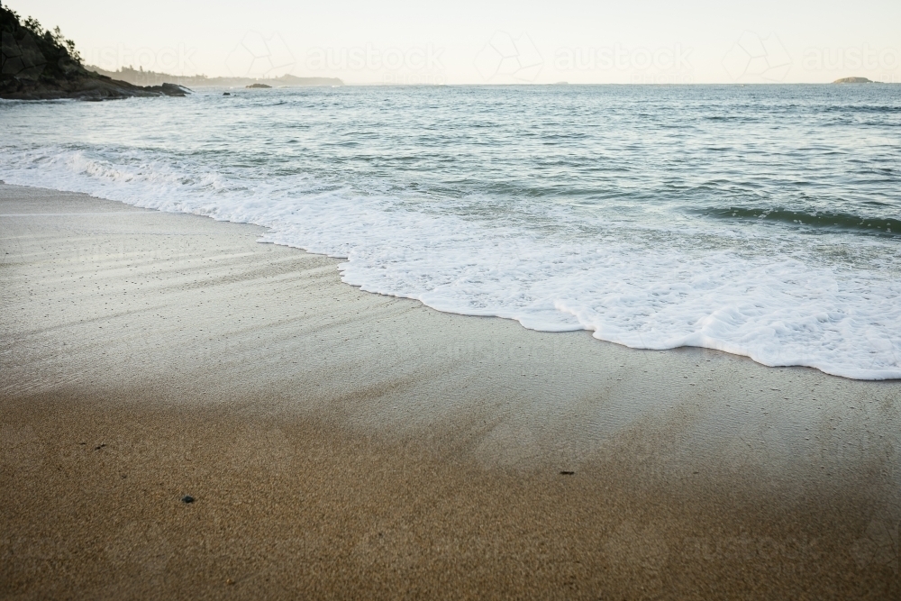 Beach with brown sand and small waves - Australian Stock Image