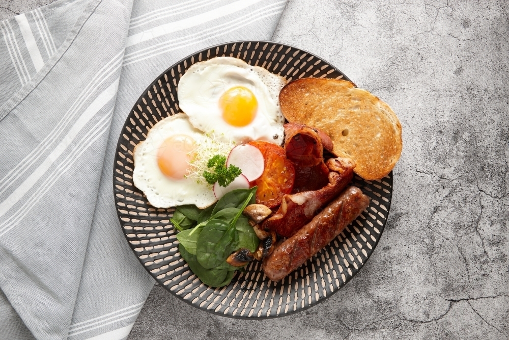 Big breakfast composed of egg, toast, tomato, meat, sausage and greens - Australian Stock Image