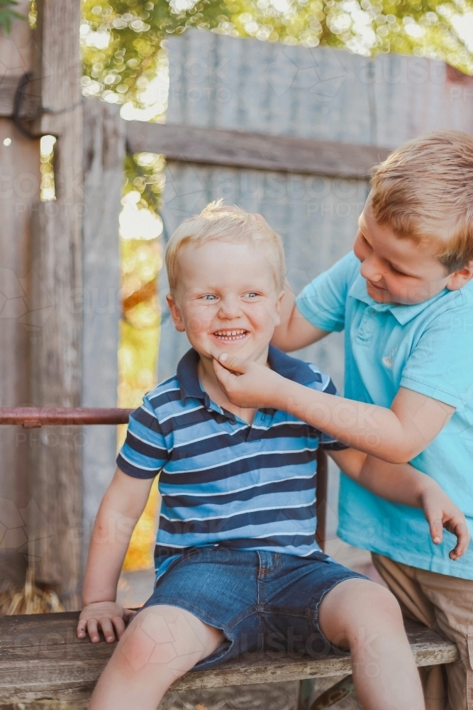 Big brother being silly making little brother smile - Australian Stock Image