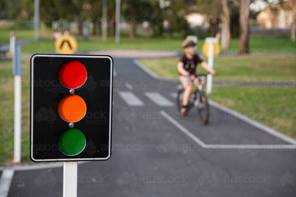 bike path with traffic signals and signs with a child riding a bike in the background - Australian Stock Image