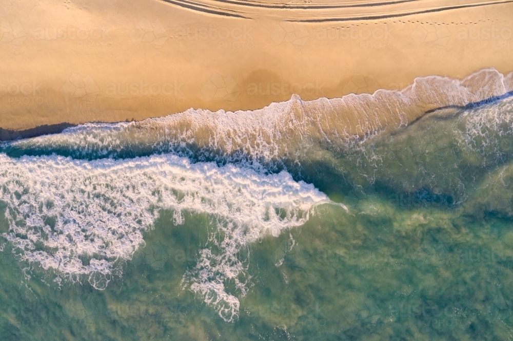 Bird's eye view of a wave on a sandy Western Australian beach. - Australian Stock Image