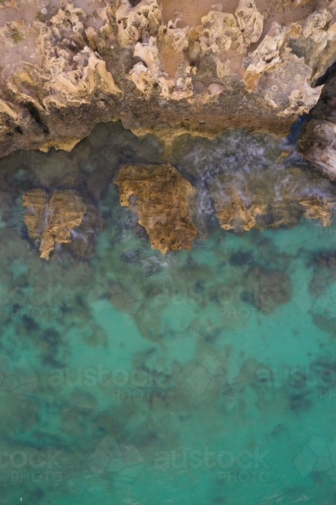 Bird's eye view of limestone cliff and rocks in blue water at Henderson Cliffs, Perth, WA - Australian Stock Image