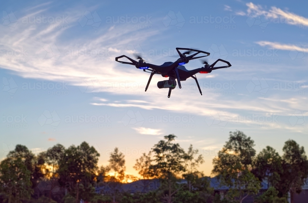 Black Drone flying at sunset in a park with copy space UAV, RPAs - Australian Stock Image