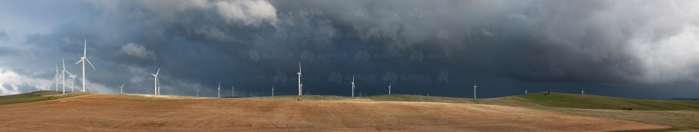 black storm clouds behind wind turbines - Australian Stock Image