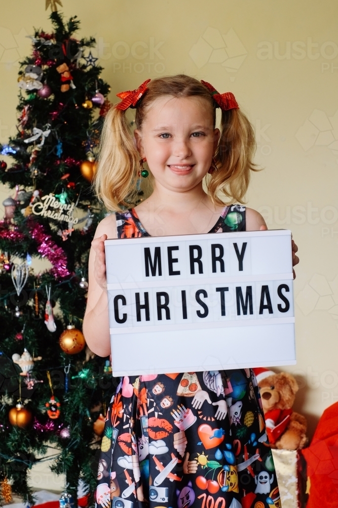 Blonde girl holding a Merry Christmas sign - Australian Stock Image