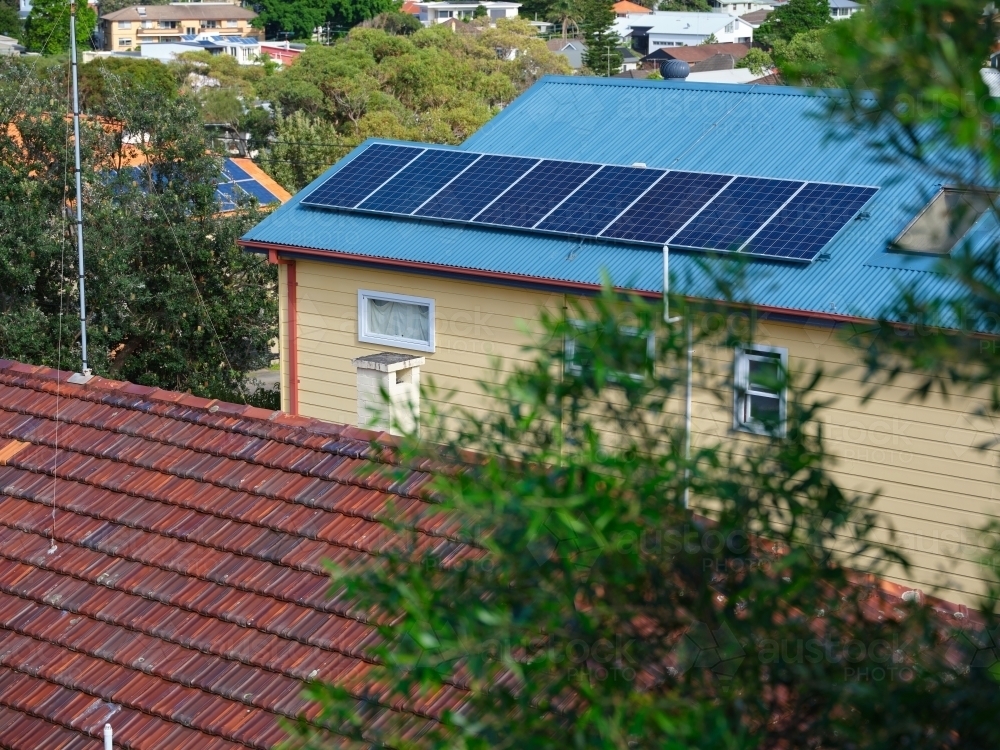 Blue colored roof with solar panels and a view with houses - Australian Stock Image