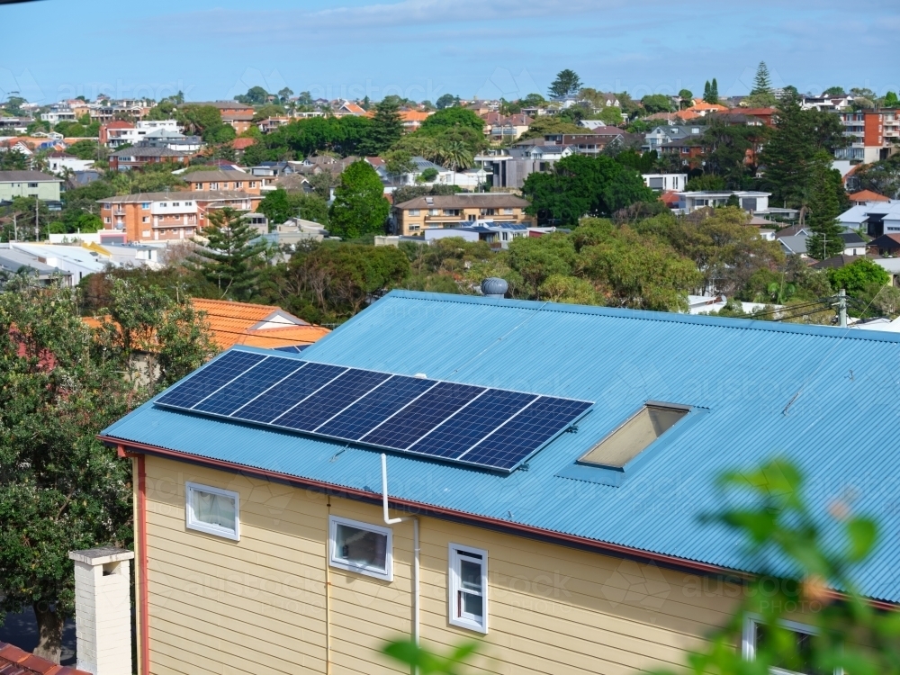 Blue colored roof with solar panels and a view with houses - Australian Stock Image