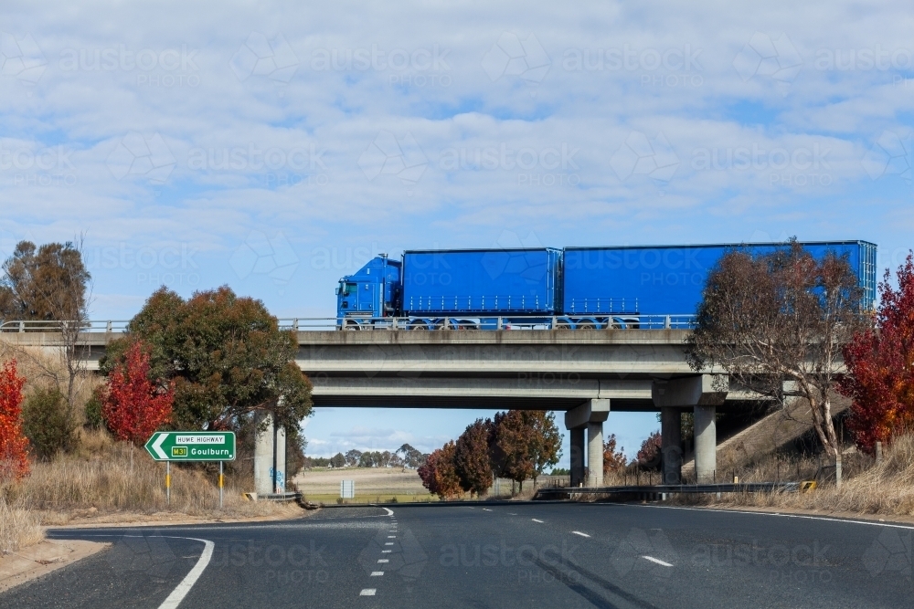 Blue truck passing on overhead overpass bridge with road sign along Hume highway to Goulburn - Australian Stock Image