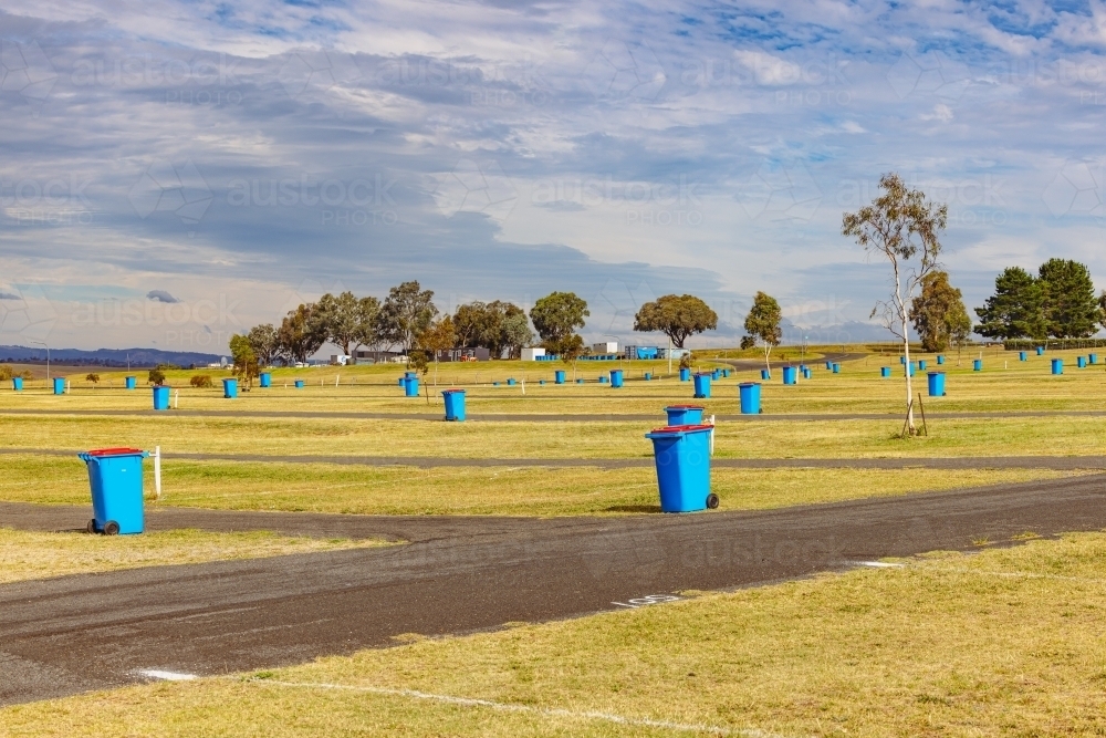 Blue wheelie rubbish bins dotted throughout grounds of Mount Panorama - Australian Stock Image