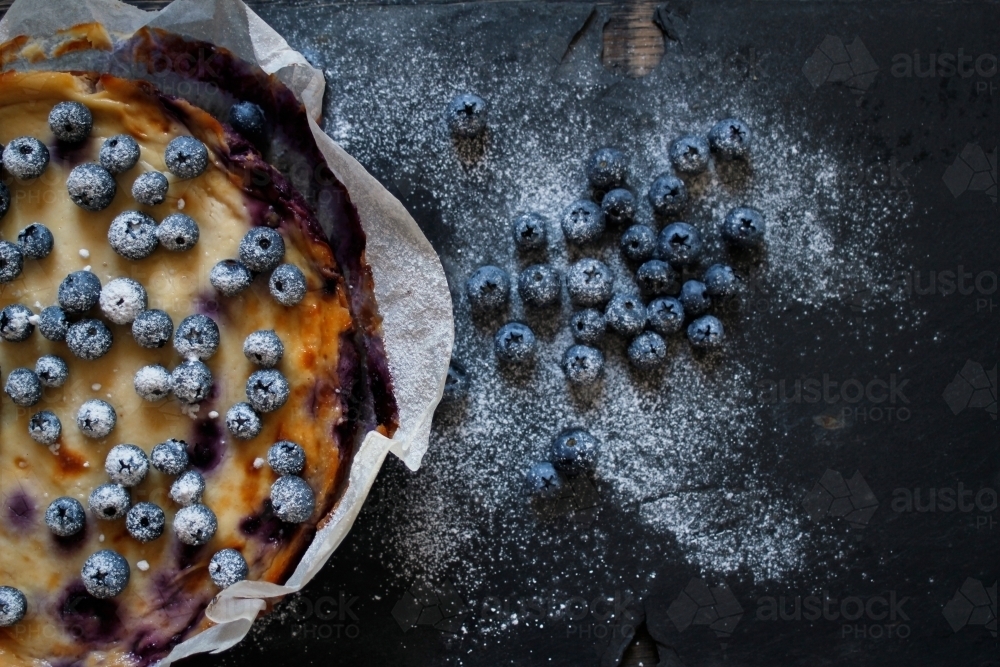 Blueberry cheesecake in baking paper on dark background - Australian Stock Image