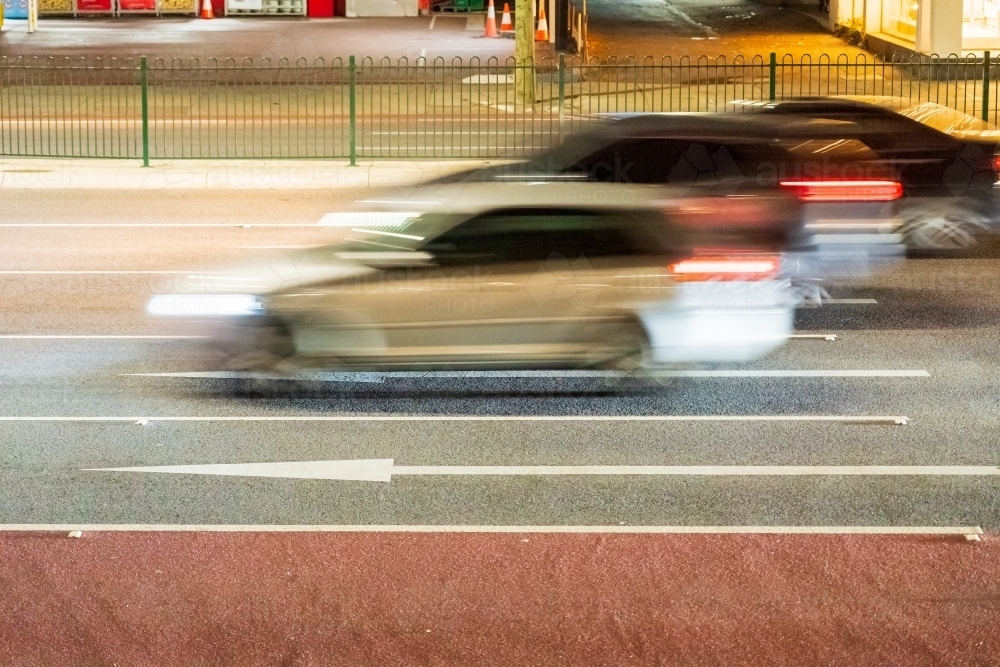 Blurred cars speeding along a busy multi lane highway after dark - Australian Stock Image