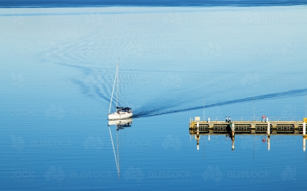 Boat coming into dock with ripples in wake - Australian Stock Image