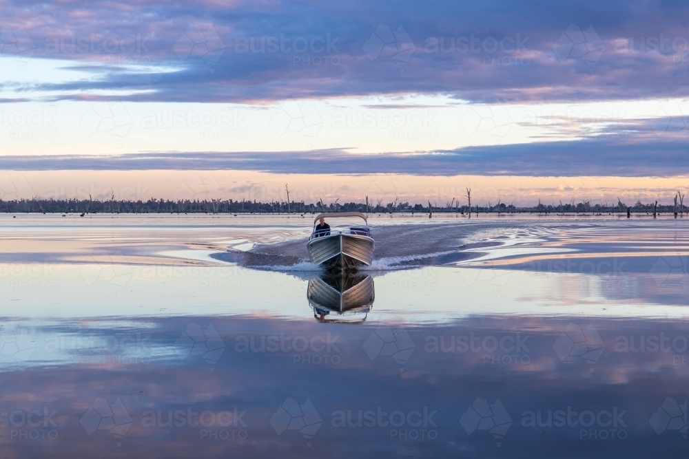 Boat moving through calm morning water - Australian Stock Image