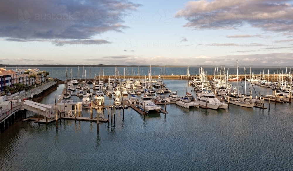 Boats anchored at sunset with dramatic clouds and dusk skyline - Australian Stock Image