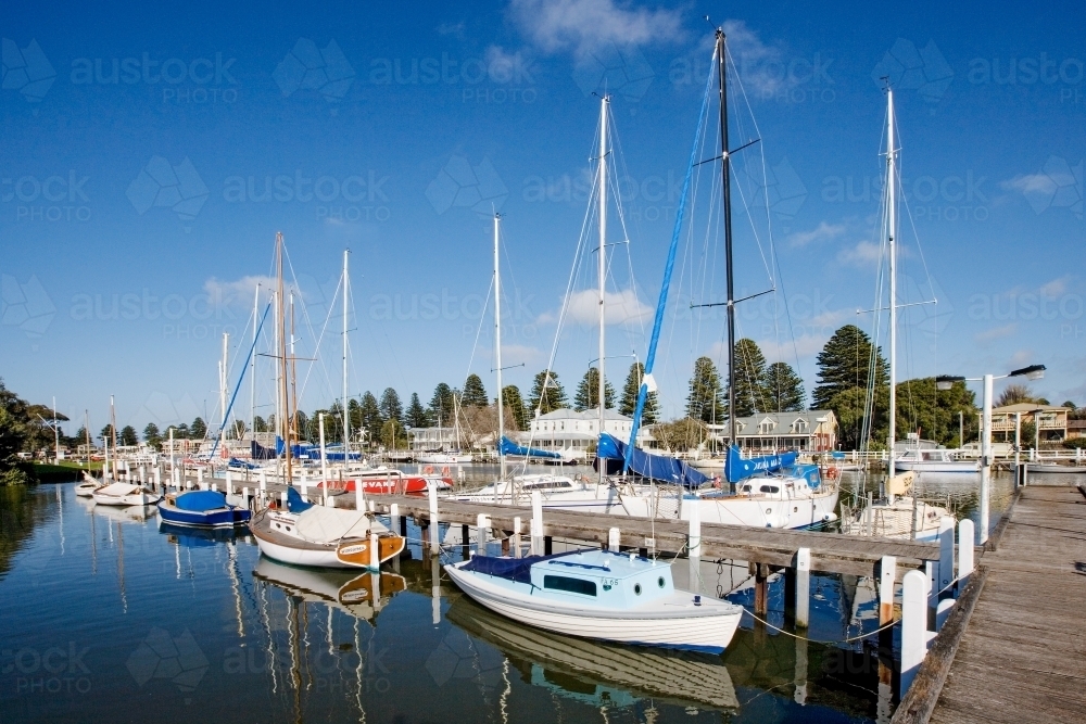 Boats moored to jetty in a heritage coastal town - Australian Stock Image