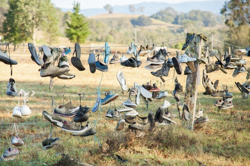 Boots and shoes hanging on fence on boot hill - Australian Stock Image