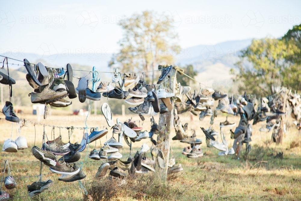 Boots and shoes hanging on fence on boot hill - Australian Stock Image