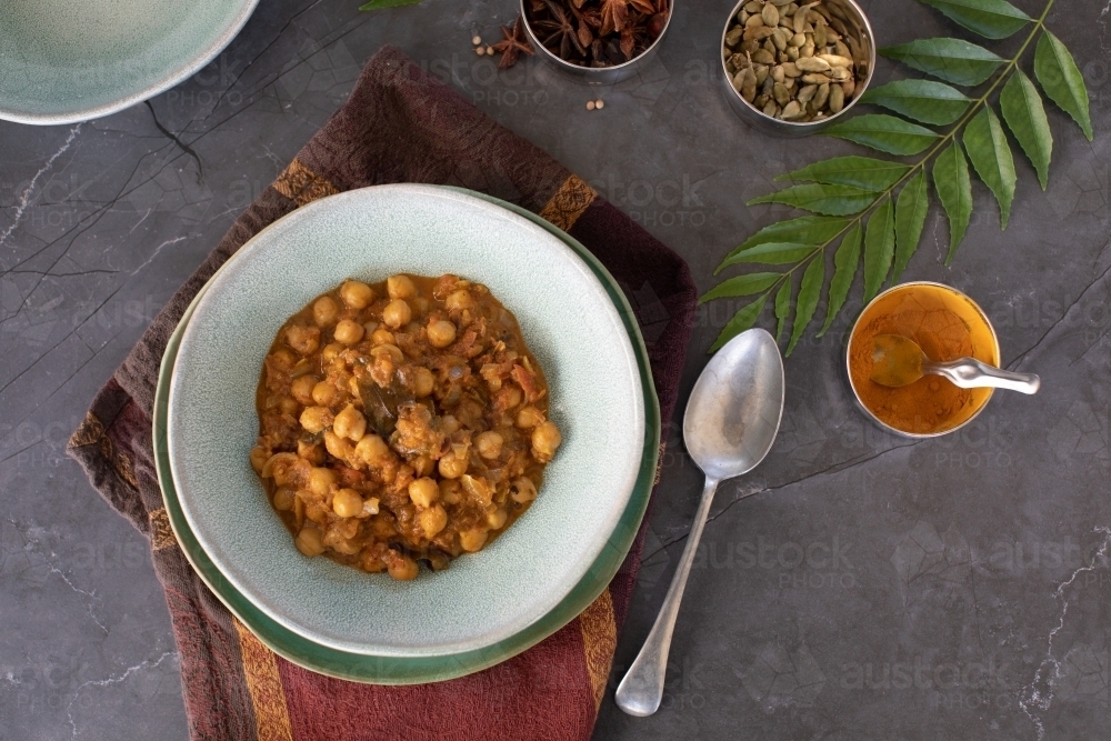 Bowl of Chickpea Curry with curry leaves and spices - Australian Stock Image