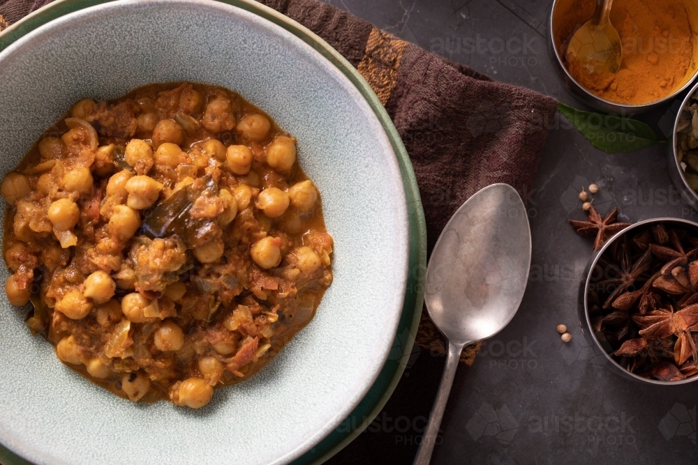 Bowl of Chickpea Curry with spices around - Australian Stock Image