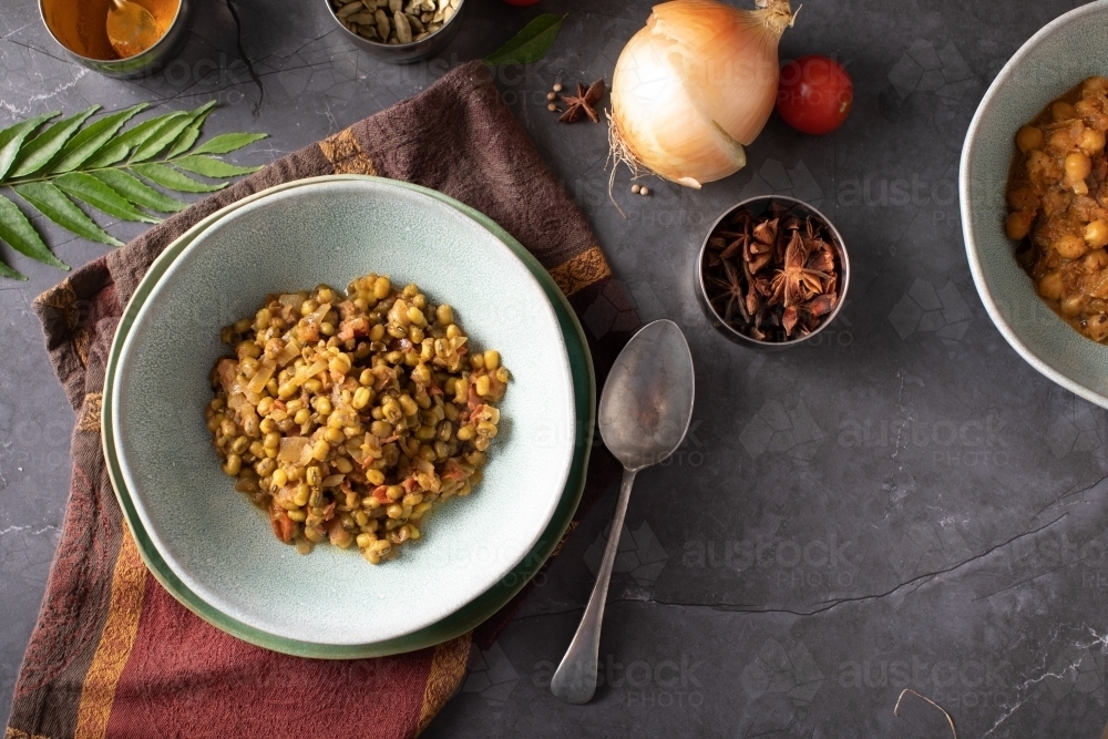 Bowl of Dahl Curry and ingredients around on dark background - Australian Stock Image